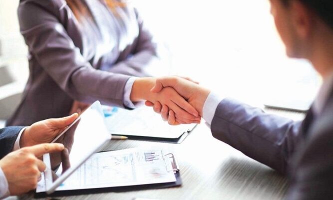 Doanh nhân bắt tay thỏa thuận hợp tác với tài liệu kinh doanh trên bàn